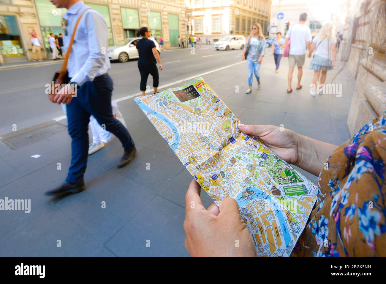 Une femme lit une carte touristique sur le trottoir d'une rue animée à Rome, en Italie Banque D'Images