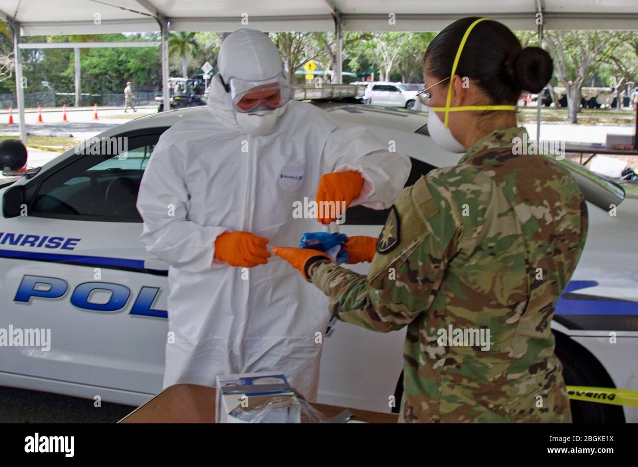 La Garde nationale de Floride SPC. John Larson (à gauche), avec le détachement médical de Floride, place une collection dans un sac à risque biologique sur un site d'essais de la communauté COVID-19, le 19 mars 2020. Le premier site d’essais communautaires COVID-19 de South Florida est situé au parc C. B. Smith. Banque D'Images