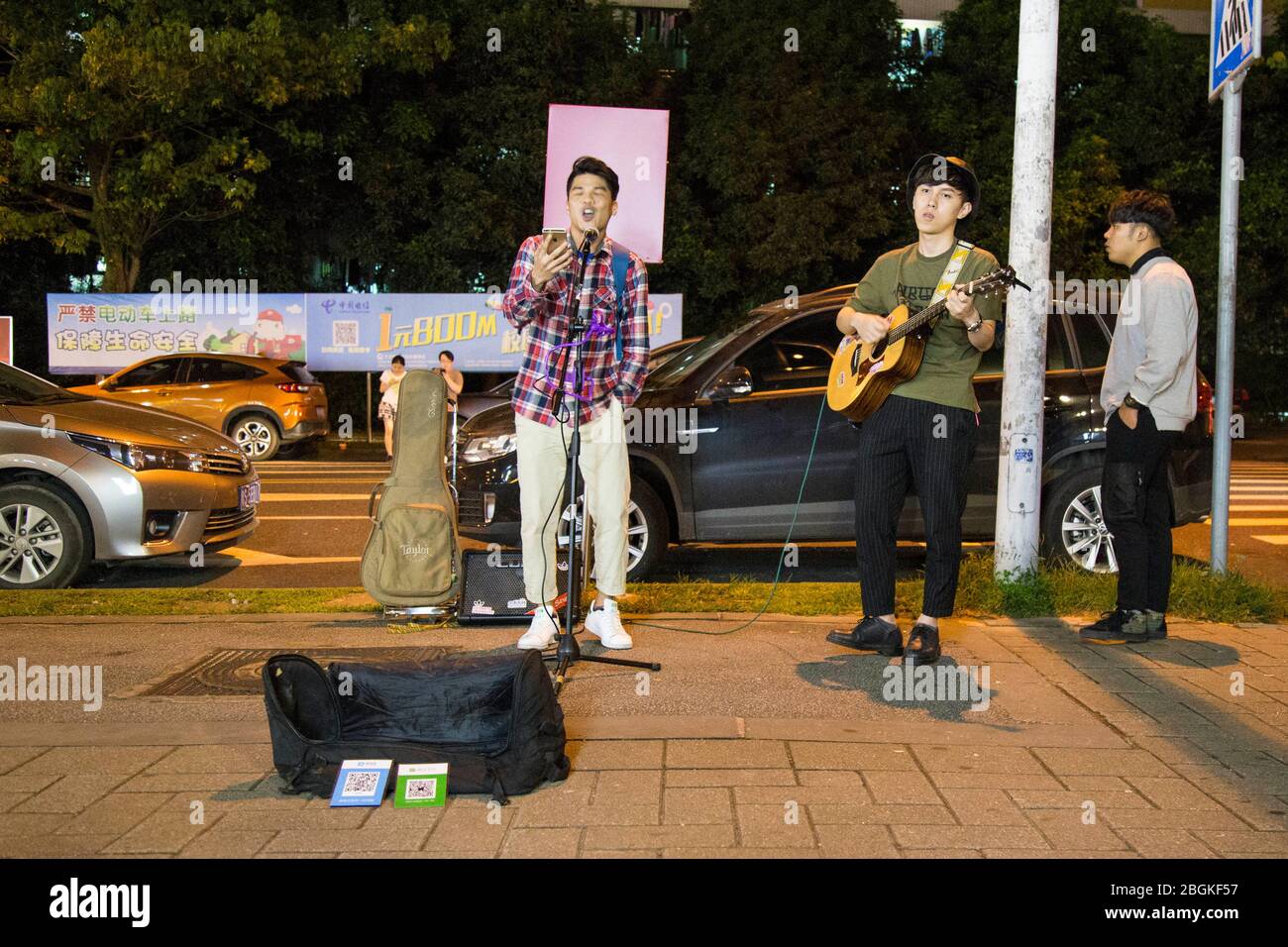 --FILE--deux jeunes hommes chantent dans la rue avec le code QR, via lequel les passants peuvent transférer de l'argent pour les soutenir, ville de Guangzhou, Guangdon de Chine méridionale Banque D'Images