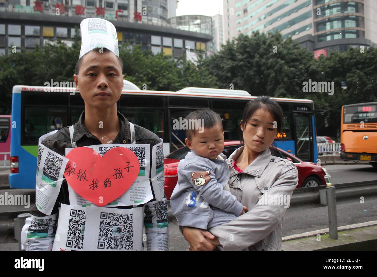 --FILE--un homme qui est couvert par le code QR via lequel il demande aux piétons de faire don pour sauver son fils aveugle, avec ses familles, Chongqing, Chine, 1 Banque D'Images