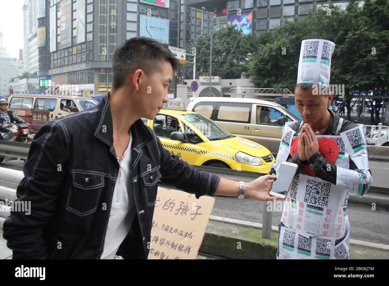 --FILE--un homme qui est couvert par le code QR via lequel il demande aux piétons de faire don pour sauver son fils aveugle, avec ses familles, Chongqing, Chine, 1 Banque D'Images