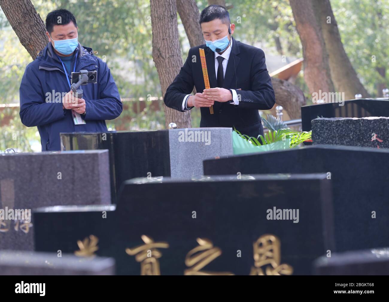 Un personnel d'un cimetière local balaie et adore en ligne la tombe pour mémoriser l'ancêtre décédé pour les clients avec son collègue qui a tiré l'OMS Banque D'Images