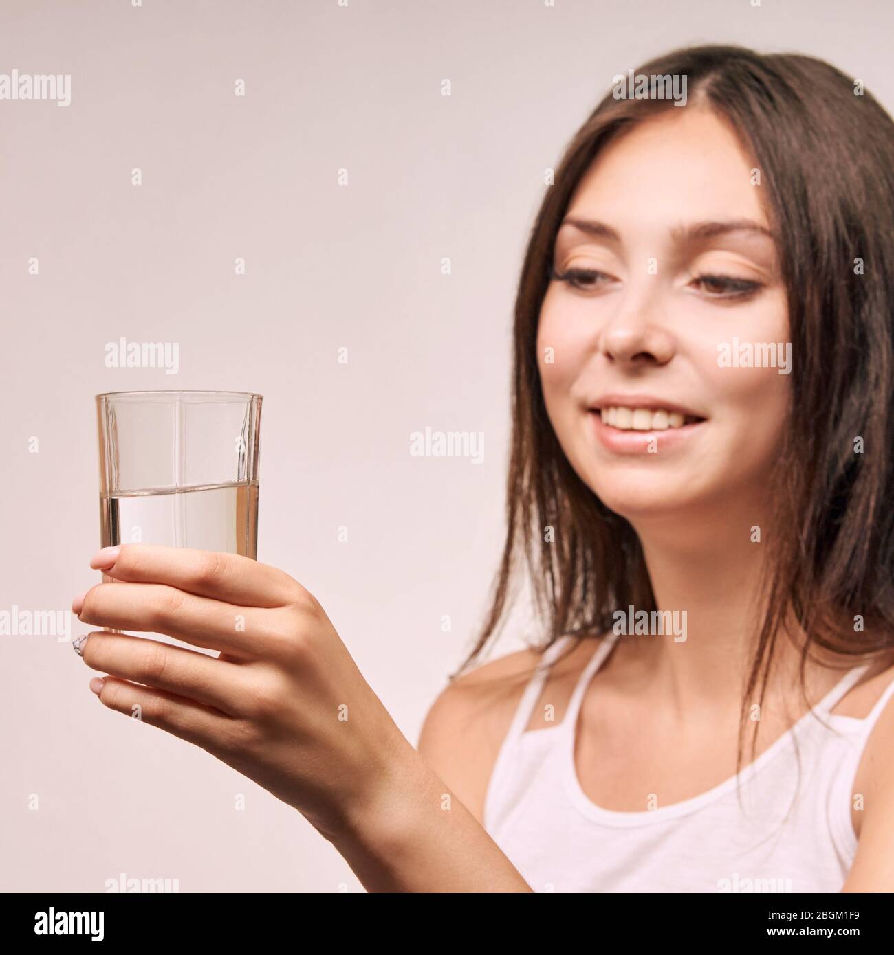 Jeune fille magnifique qui tient du verre d'eau. Hydrate visage femelle. Les femmes heureuses à l'intérieur Banque D'Images