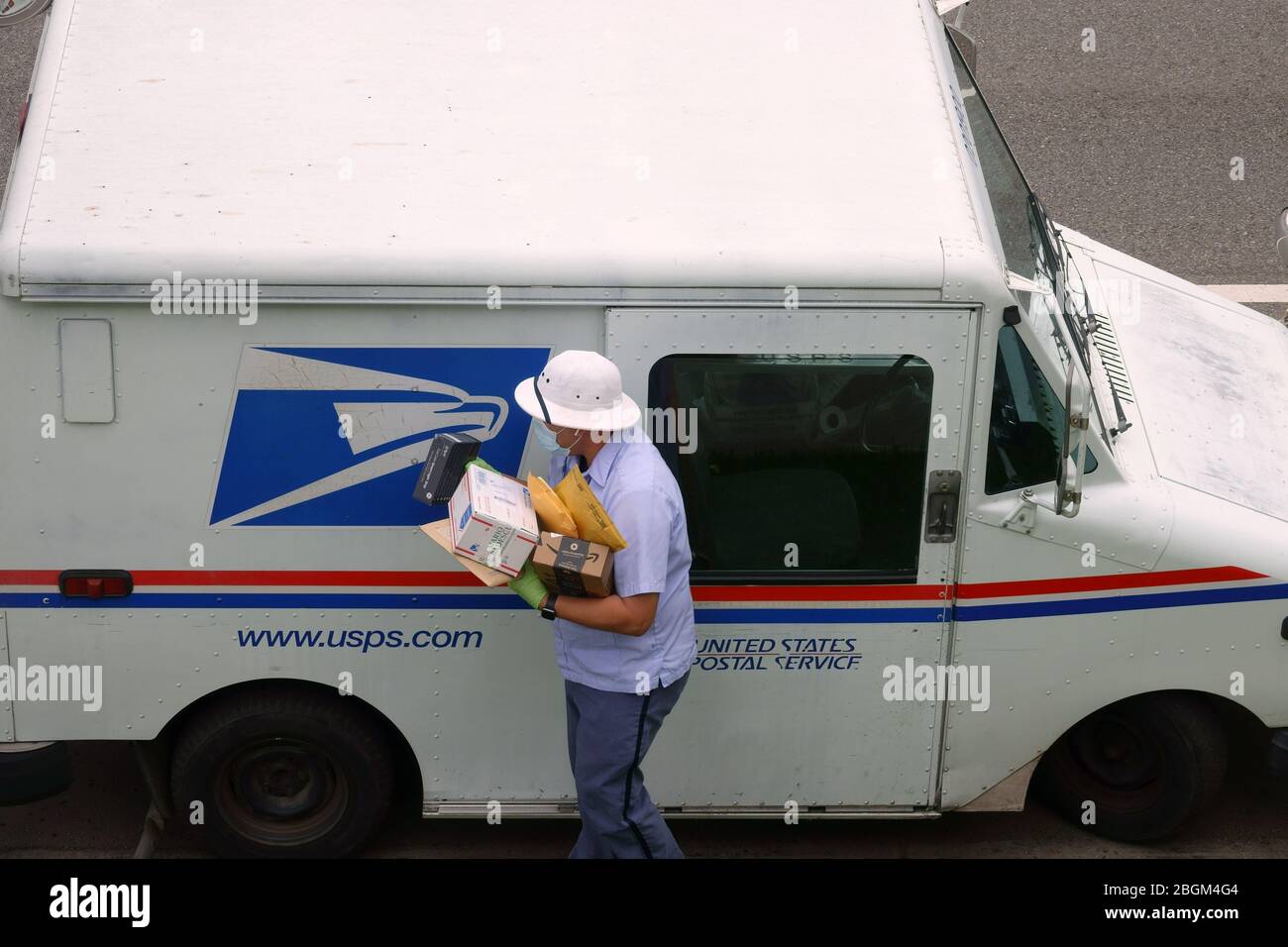 Los Angeles, CA / USA - 20 avril 2020: Un transporteur de courrier pour le Service postal des États-Unis USPS porte un masque et des gants pendant la pandémie COVID-19. Banque D'Images