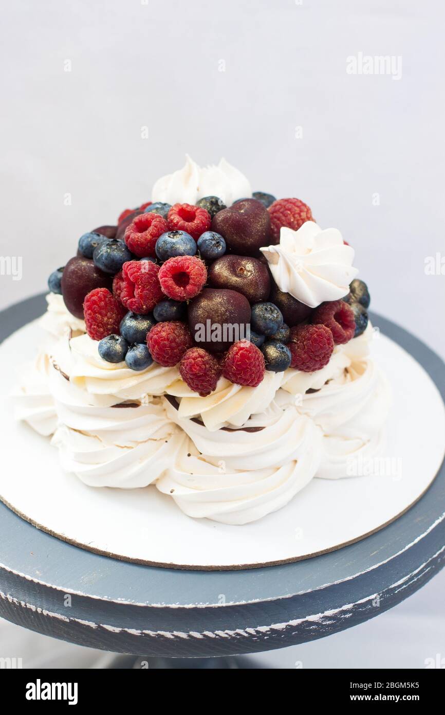 Gâteau de fingue Pavlova avec sauce au chocolat, crème fouettée et cerises fraîches, fraises, bleuets. Banque D'Images