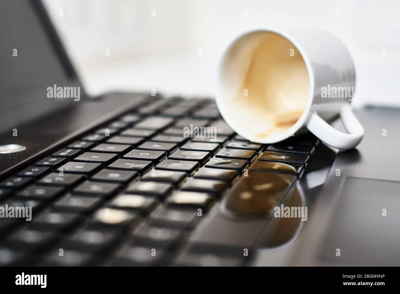 Renversez du café dans la tasse blanche sur le clavier de l'ordinateur portable. L'ordinateur est endommagé en raison d'un liquide renversé Banque D'Images Renversez du café dans la tasse blanche sur le clavier de l'ordinateur portable. L'ordinateur est endommagé en raison d'un liquide renversé Banque D'Images