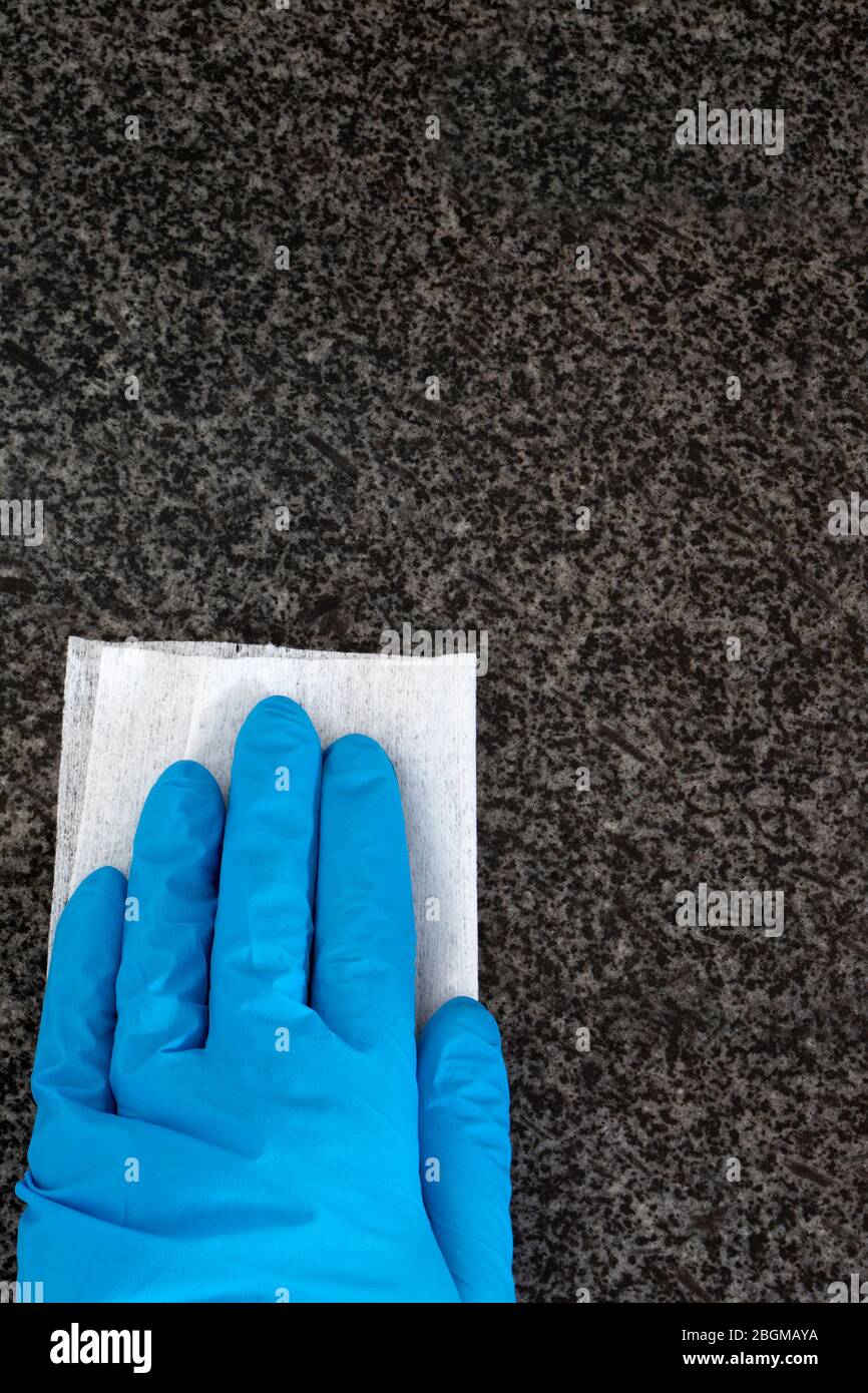 Personne portant des gants de nettoyage comptoir de travail de cuisine en granit avec un chiffon antibactérien. Tuer les bactéries et les germes concept Banque D'Images