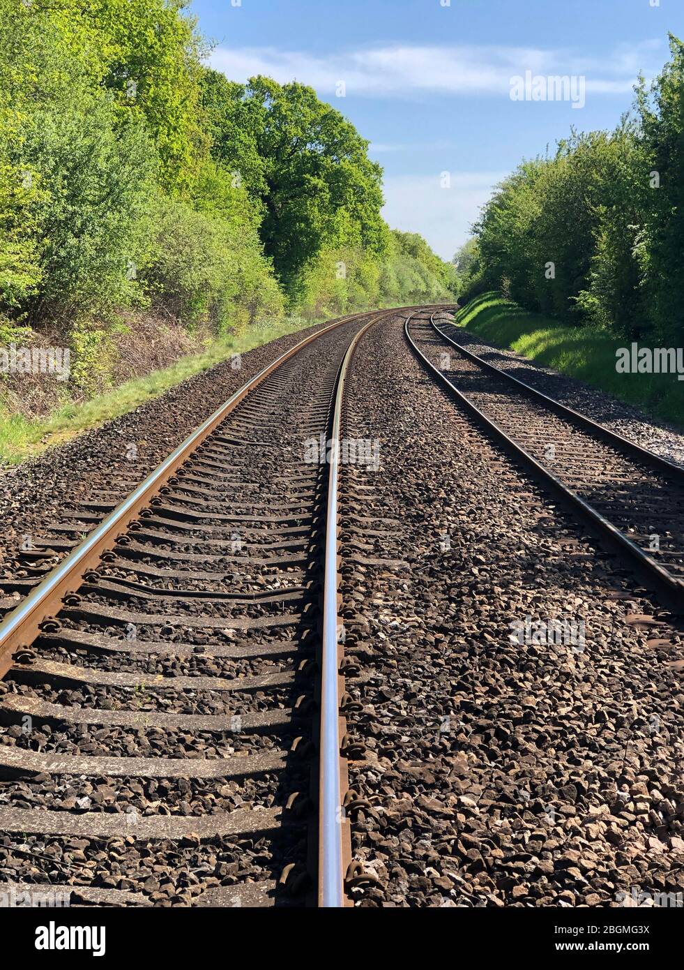 rail de train vide à lignes d'arbre symétriques verticales, propre aux marquages qui mènent à la courbe dans le ciel bleu du pays pour l'idée d'espace de copie pour l'affiche ou le sommet Banque D'Images