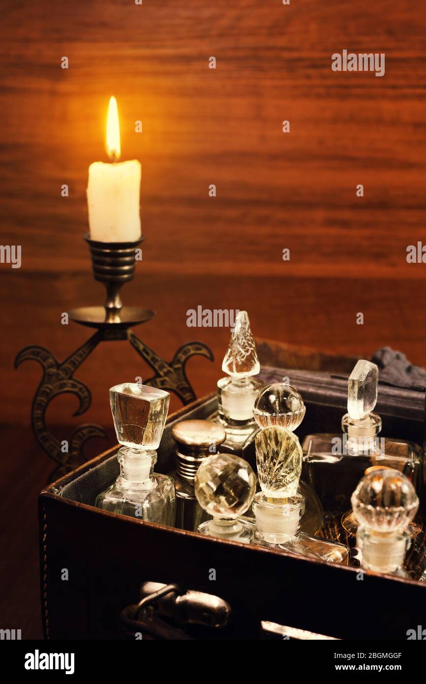Bougie dans le chandelier de couleur bronzée et diverses bouteilles de parfum vintage dans l'ancienne grippack en cuir Banque D'Images