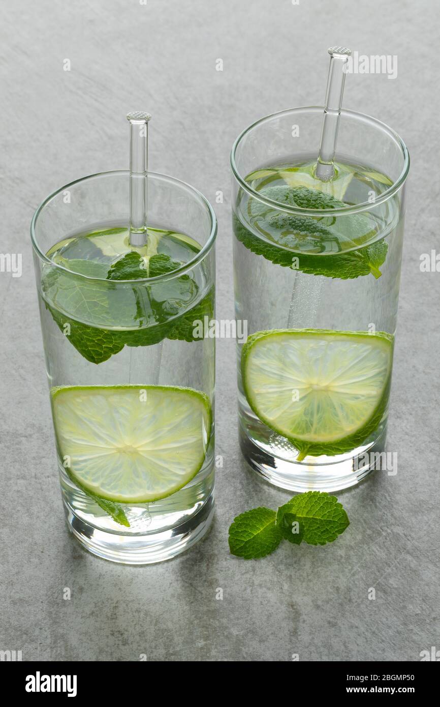 Paire de verres d'eau avec une tranche de citron vert et de feuilles de menthe fraîche Banque D'Images
