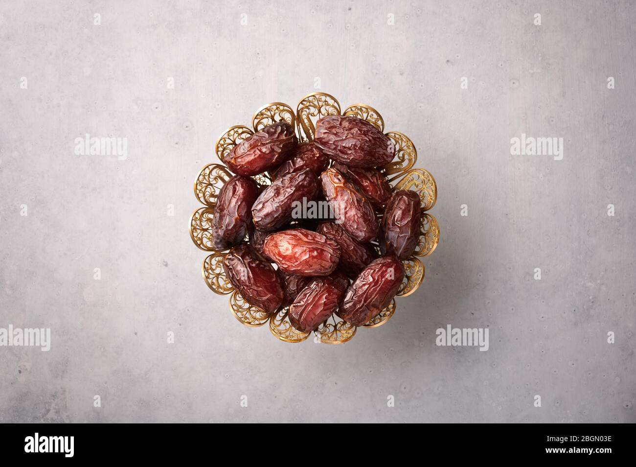 Datez les fruits ou le Kurma dans la plaque de bronze sur fond de béton gris. Les dates sont la nourriture du Ramadan. Nourriture de Ramazan Iftar. Banque D'Images