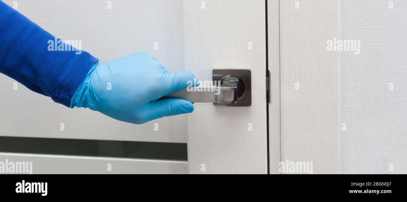 La main pour homme dans un gant de protection bleu s'ouvre ou ferme la porte. Bannière antibactérienne de prophylaxie en temps de virus et d'infections. Santé et Banque D'Images