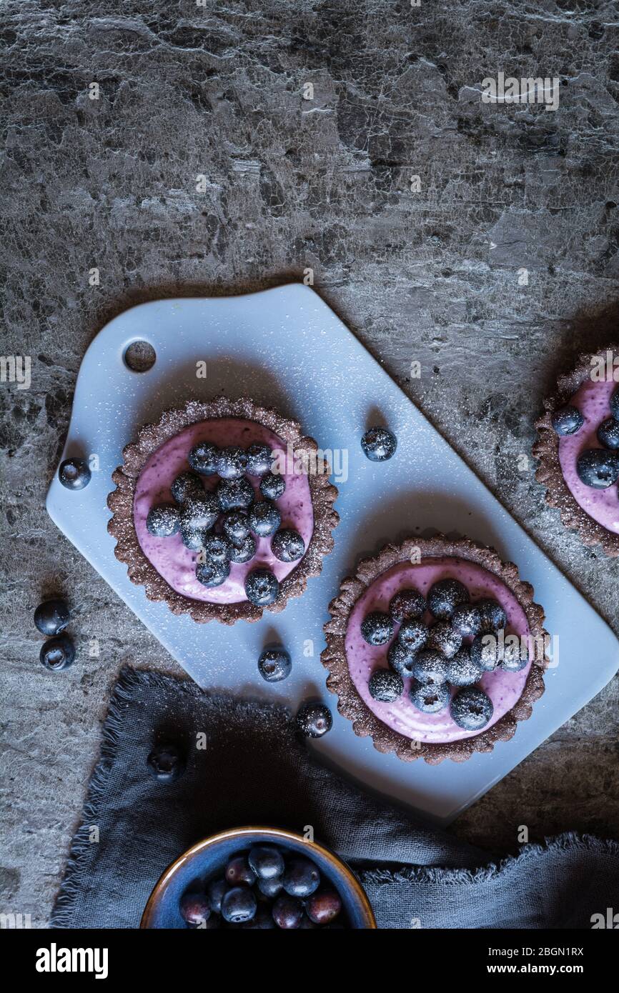 Tartelettes au chocolat remplies de crème mascarpone aux bleuets et de sucre en poudre Banque D'Images
