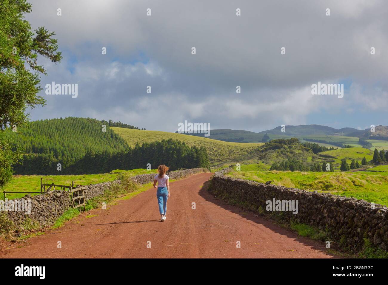 Jeune femme marcher au chemin de campagne. Les champs marqués d'un ciel bleu. Terceira Banque D'Images