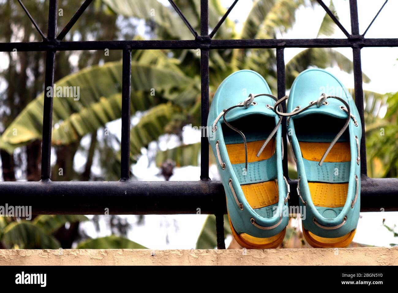 Photo d'une plage de sandales en caoutchouc coloré sur une clôture, une journée claire et ensoleillée. Banque D'Images
