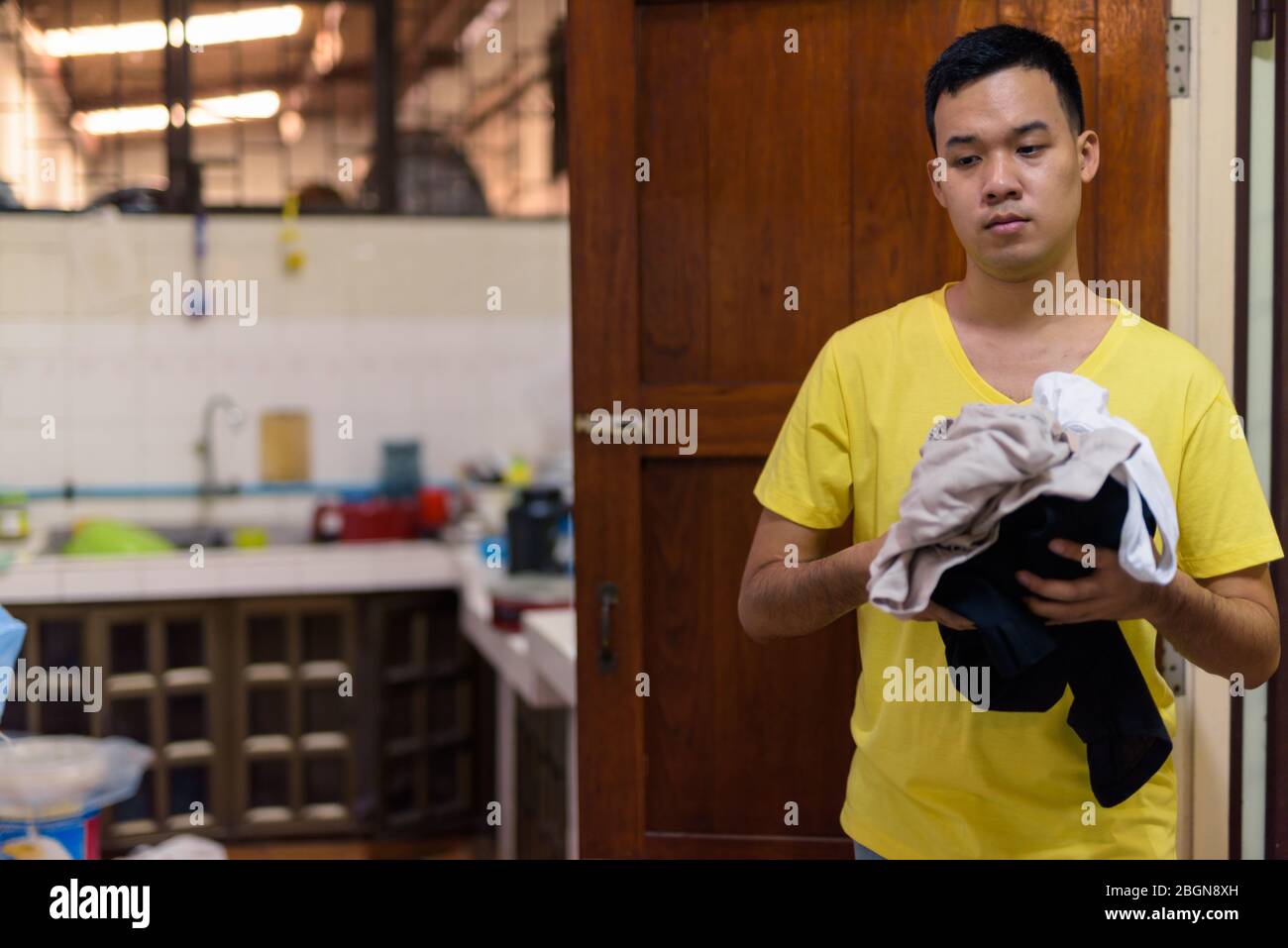 Portrait de jeune homme asiatique laver des vêtements à la maison Banque D'Images