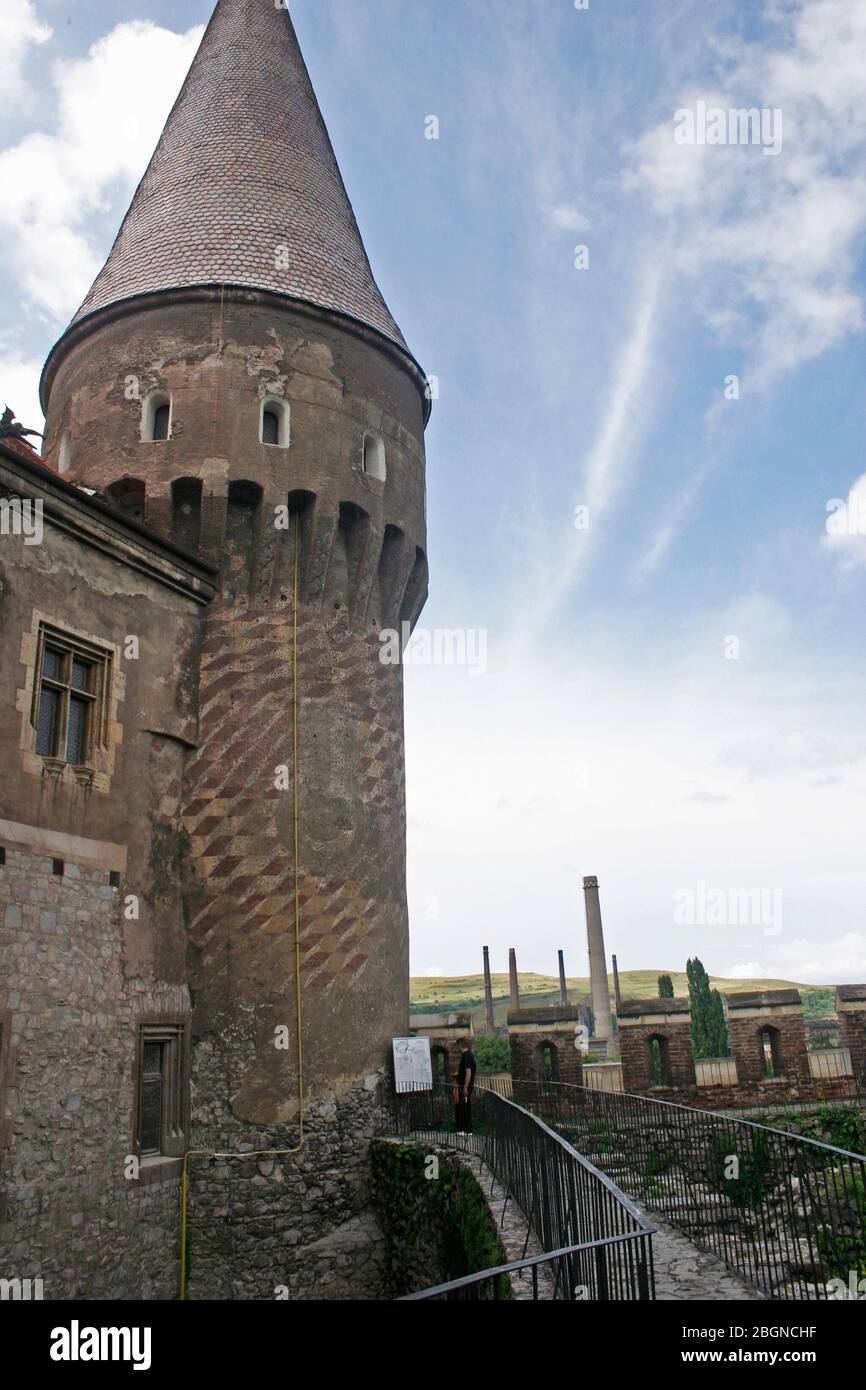 Hunedoara, Roumanie. Vue contrastée du château historique de Corvin vers le moulin en acier adjacent, avec ses cheminées. Banque D'Images