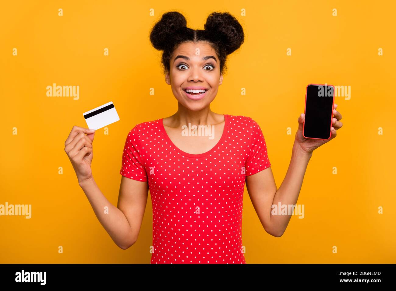 Choqué surpris afro american girl promoteur tenir carte de banque de téléphone portable impressionné incroyable facile de paiement de service de transfert en ligne porter rouge pointillé t Banque D'Images