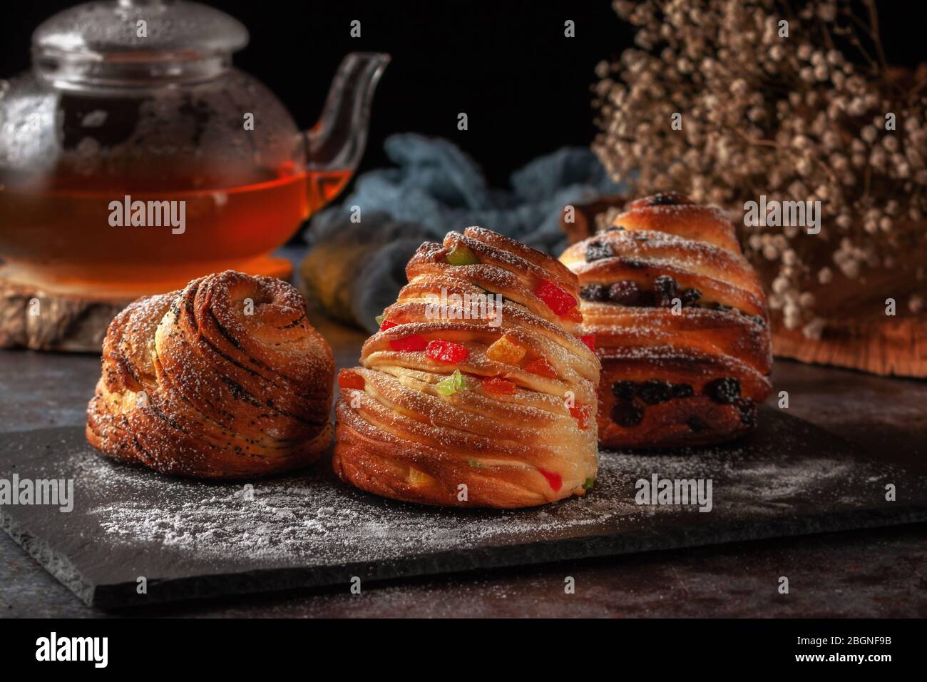 Kraffins aux raisins secs, fruits confits et graines de pavot, arrosés de sucre en poudre. Banque D'Images
