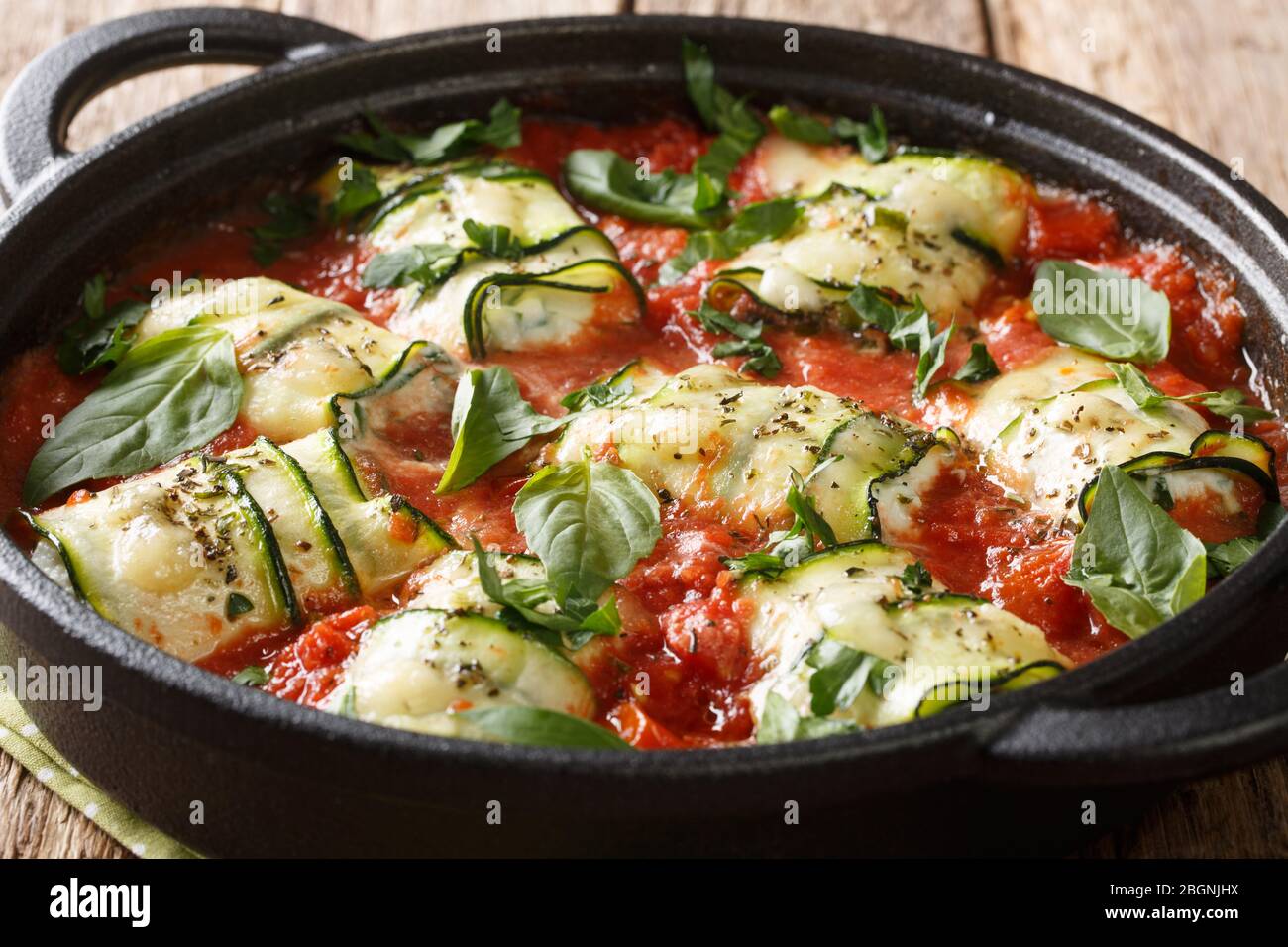 Plats italiens courgettes cuites au fromage ricotta et herbes dans la sauce tomate dans une poêle sur une table de gros plan. Horizontal Banque D'Images