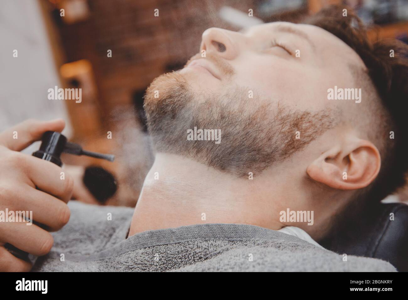 Le Barber traite la peau masculine avec de la poudre de talc et de la  lotion pour les blessures et l'irritation après le rasage de la barbe avec  un rasoir Photo Stock -