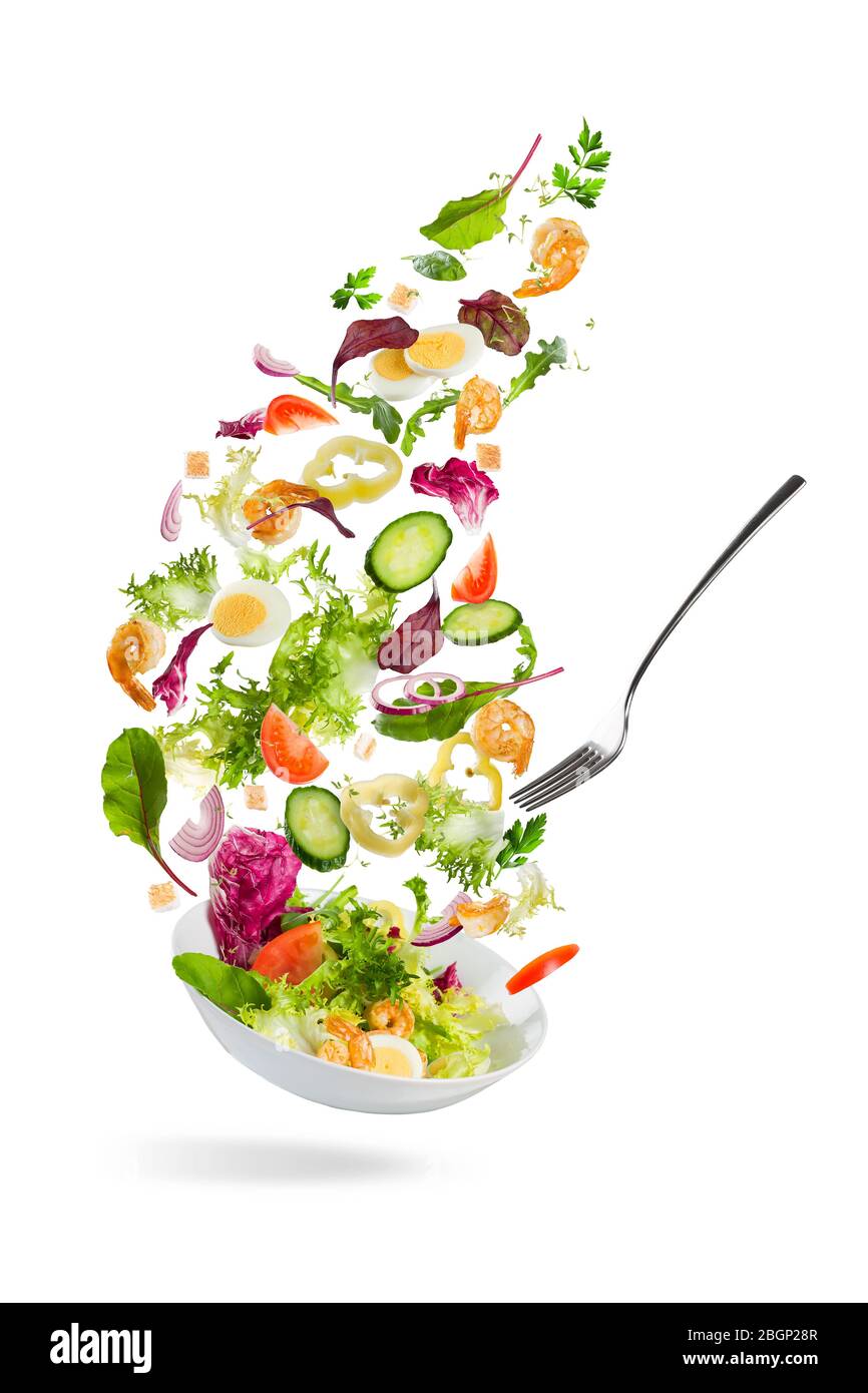 Légumes en tranches qui tombent dans un bol avec salade sur fond blanc Banque D'Images