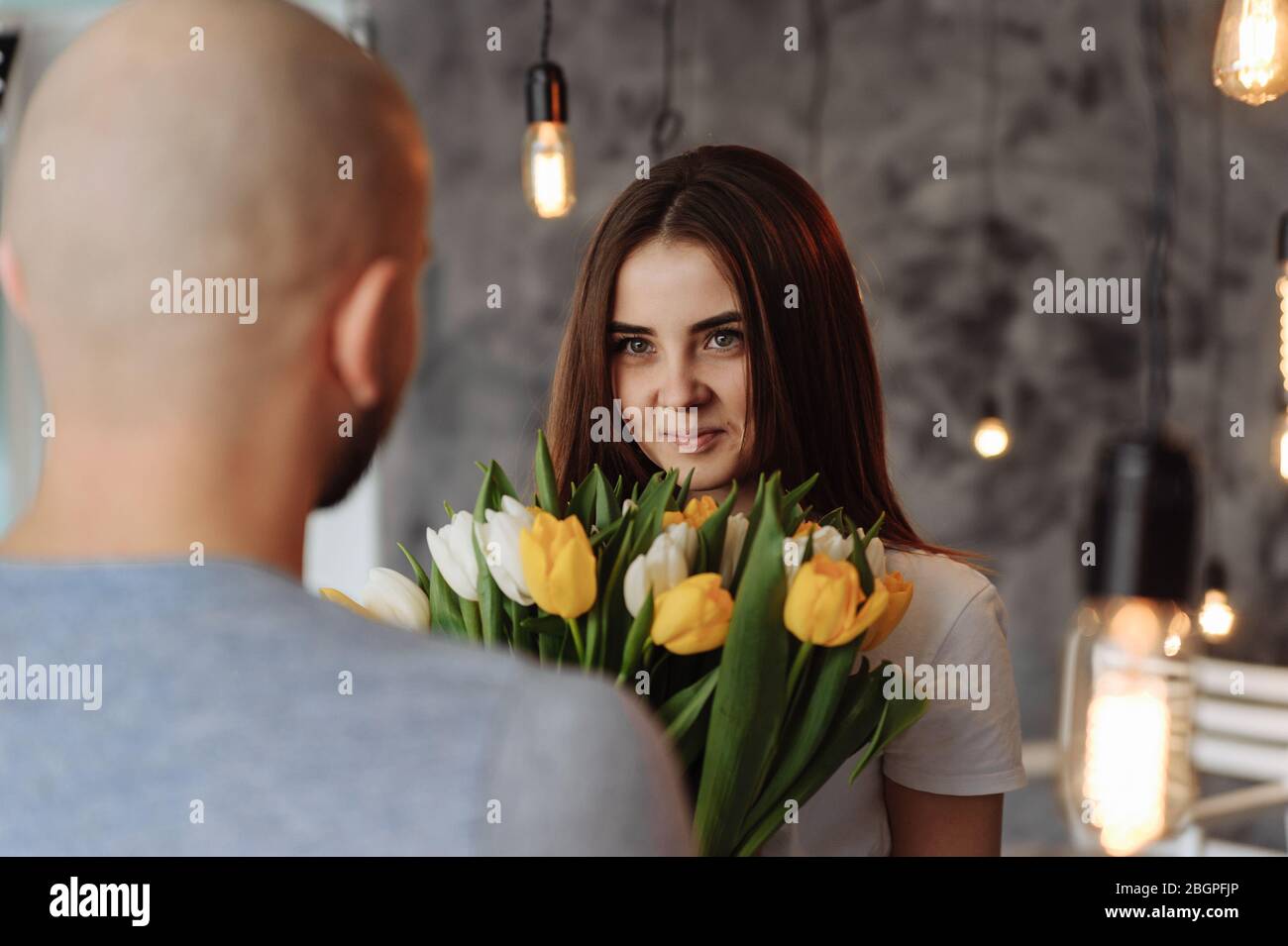 Homme donnant un bouquet de tulipes à la fille souriante Banque D'Images