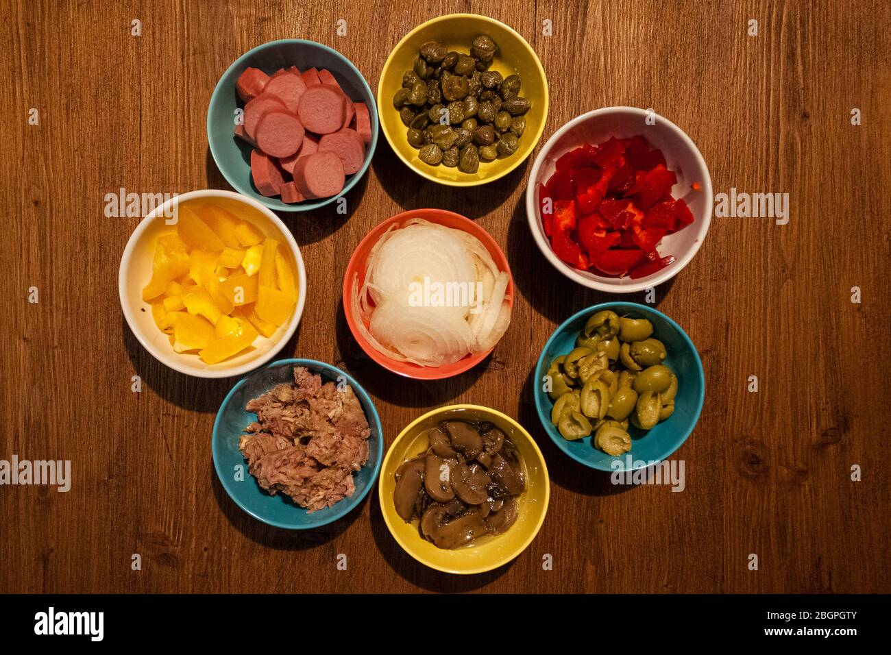 Vue de dessus des tasses avec câpres, thon, hot-dogs, oignons, poivrons, champignons, olives Banque D'Images