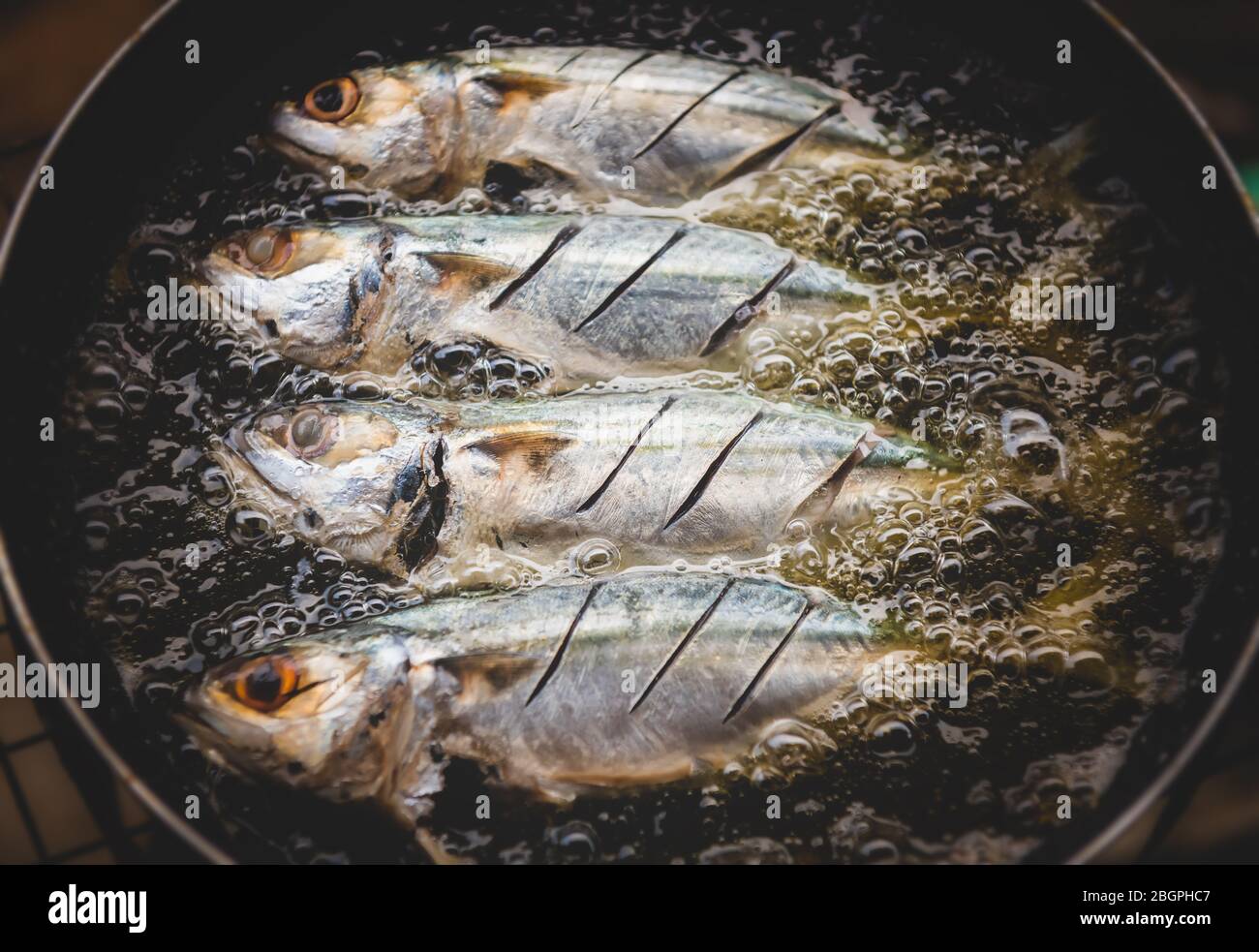 Friture poissons cuisson avec poêle à huile chaude avec éclairage intérieur bas. Banque D'Images