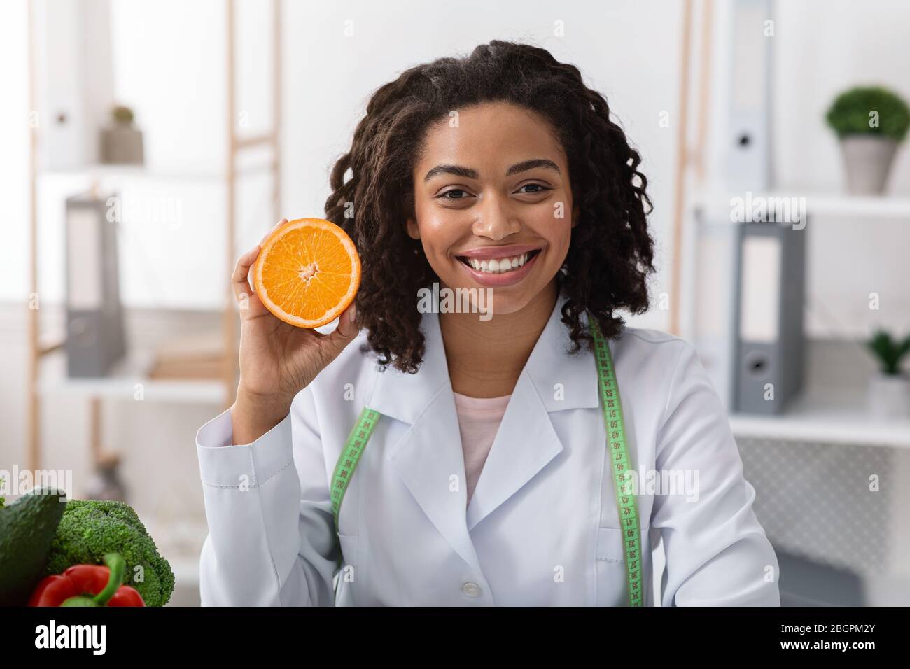 Portrait d'une femme souriante médecin tenant la moitié orange Banque D'Images