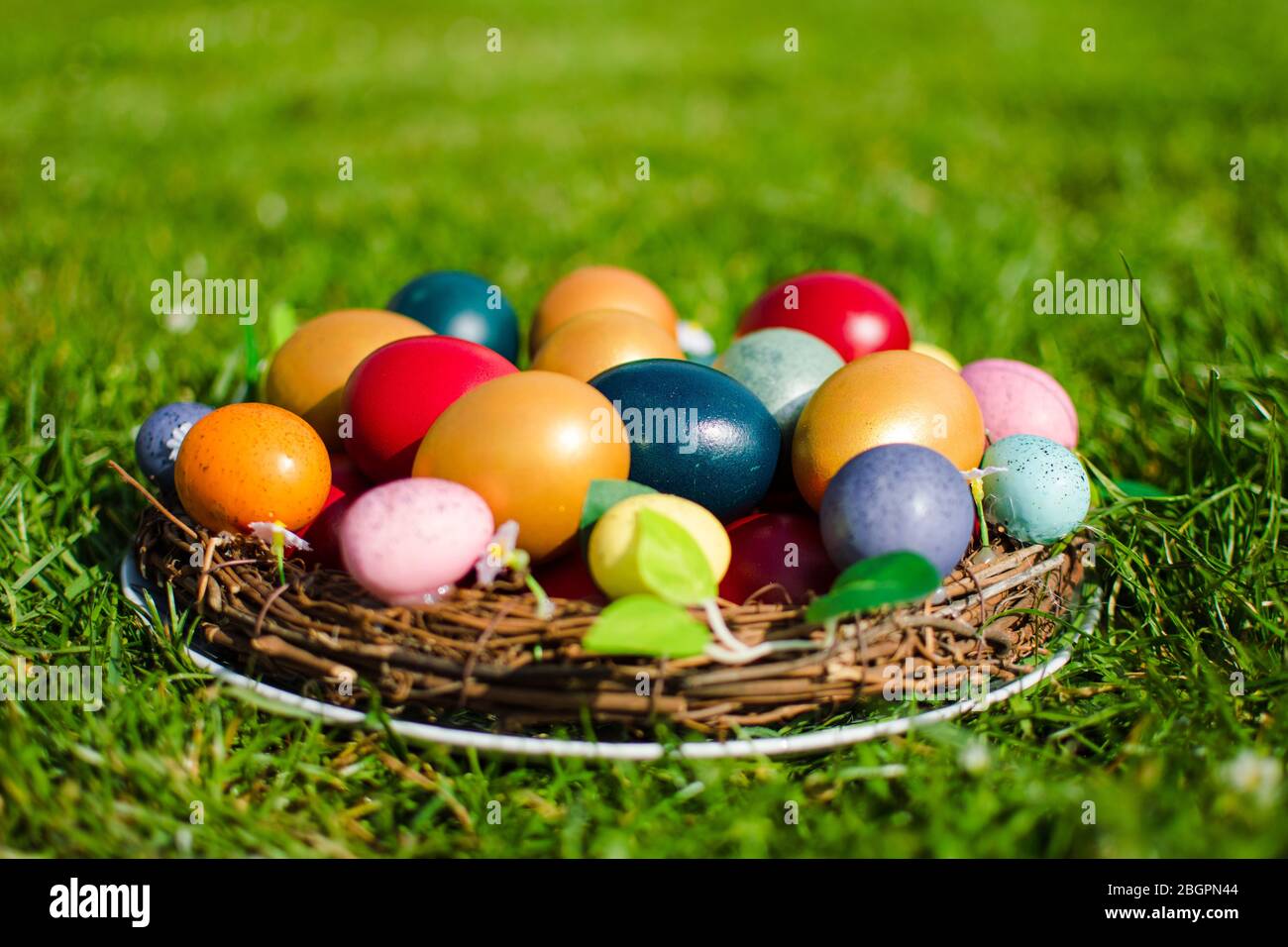 Stock photo des oeufs de Pâques dans un panier en bois sur l'herbe verte comme symbole de Pâques dans la religion chrétienne. Banque D'Images