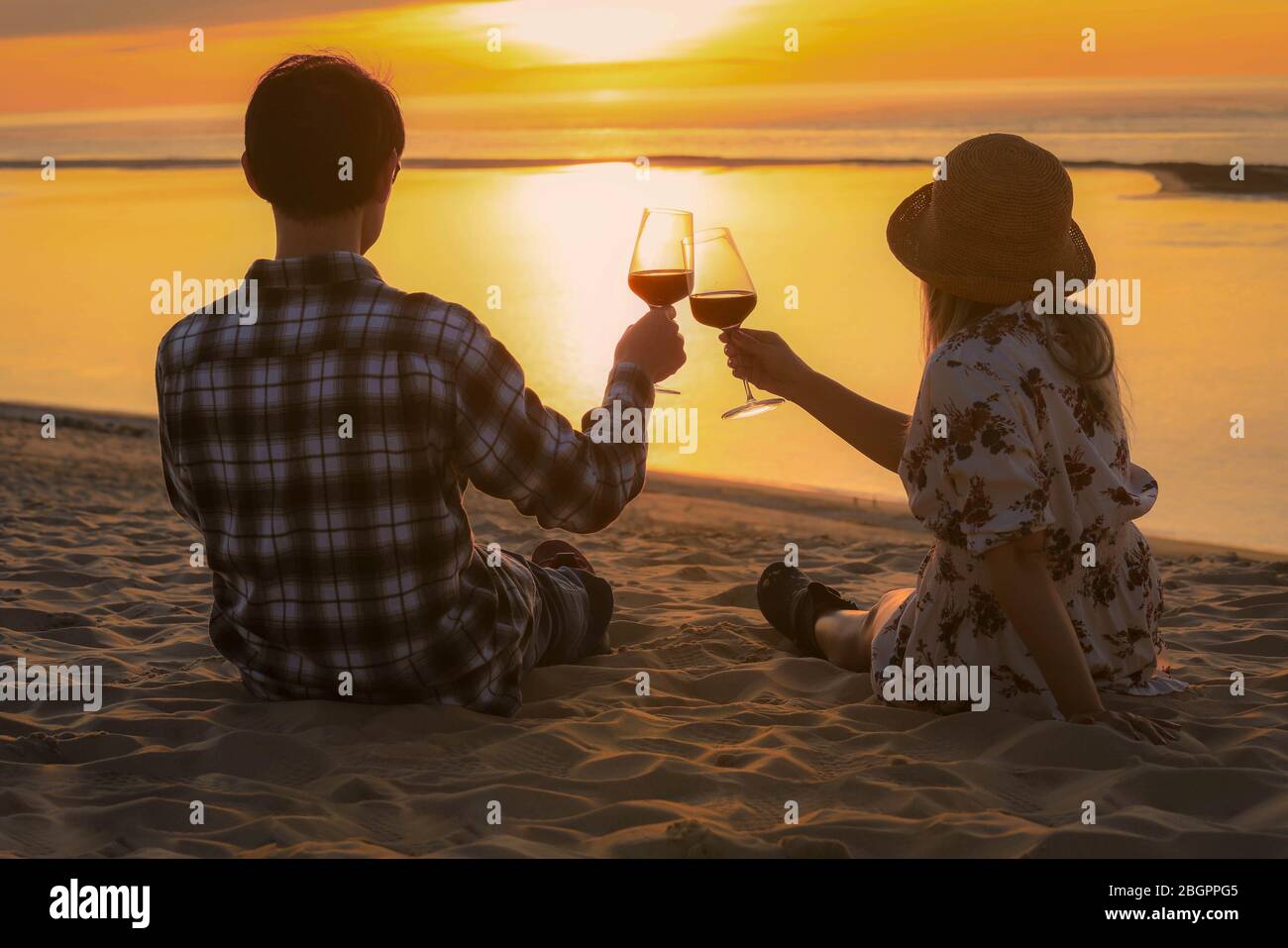 Couple célébration boire du vin rouge à la plage de coucher du soleil Banque D'Images