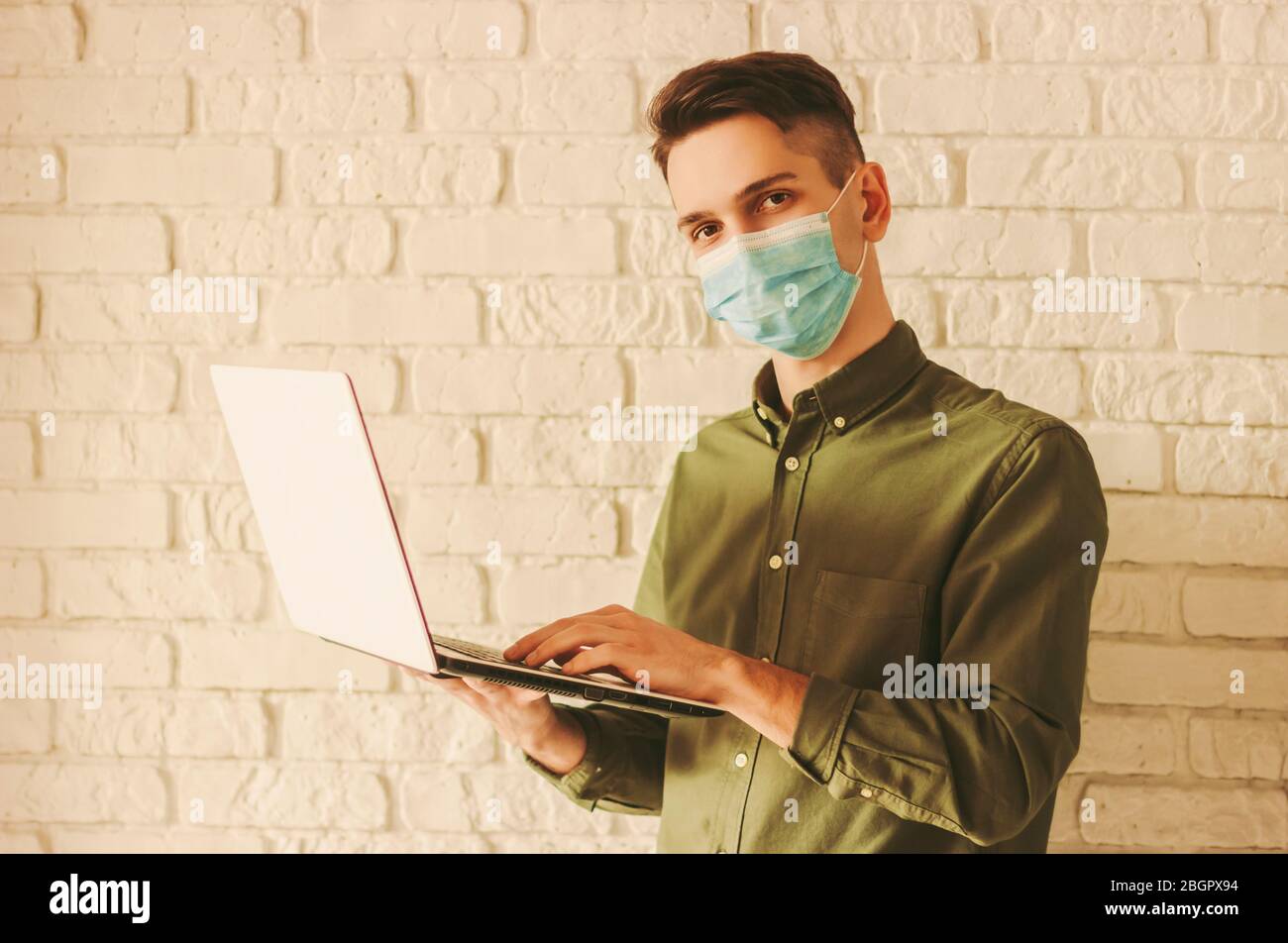 Homme d'affaires dans le masque médical travaille sur ordinateur portable à la maison. Étude à distance des étudiants Hipster sur ordinateur. Homme en masque protecteur shopping en ligne Banque D'Images