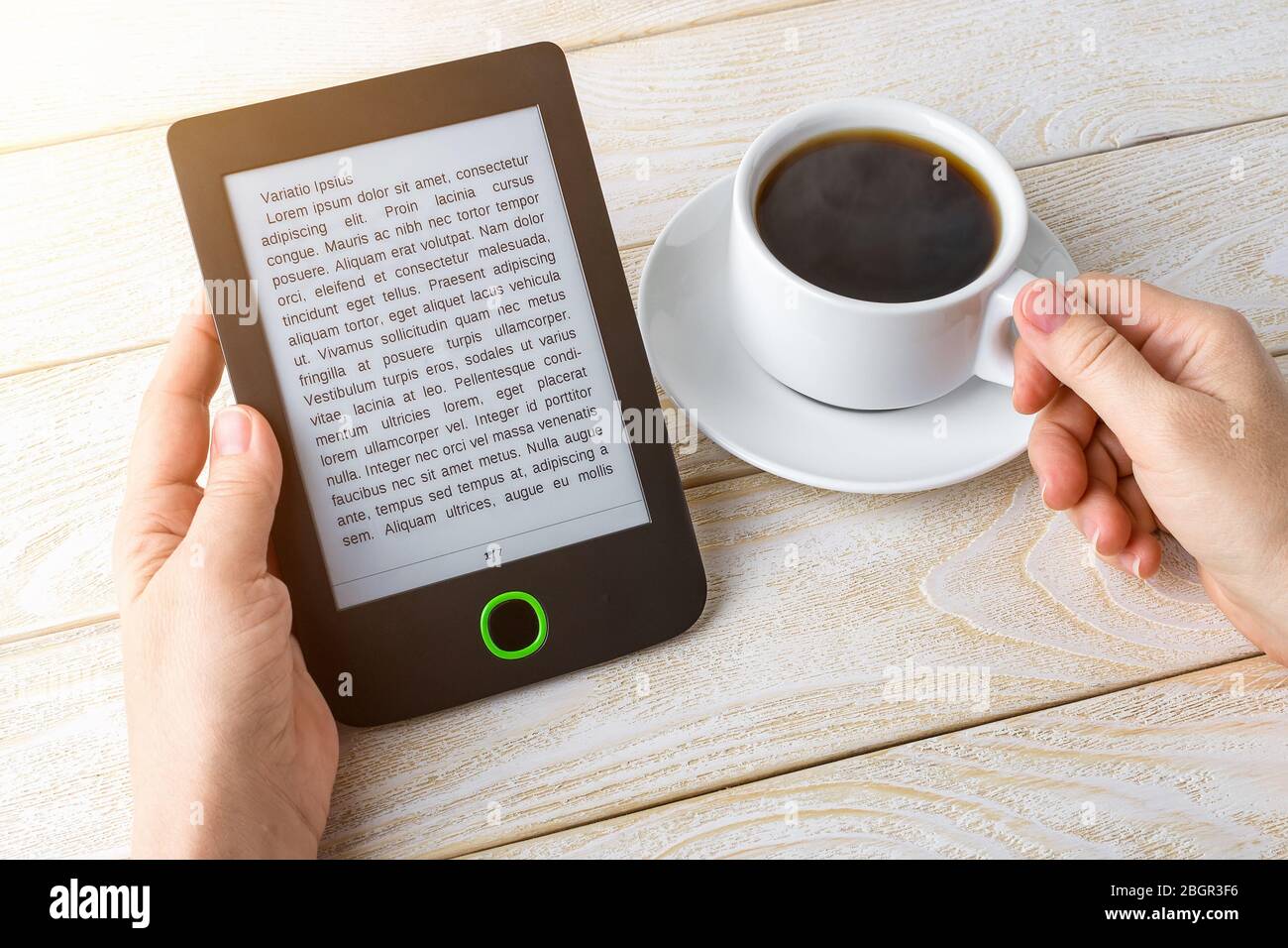 Les mains de femme tiennent e-Reader et tasse de café chaud sur une table en bois blanc . Espace de copie sur l'affichage de l'e-book. Lecture électronique pour le plaisir et l'éducation. Banque D'Images