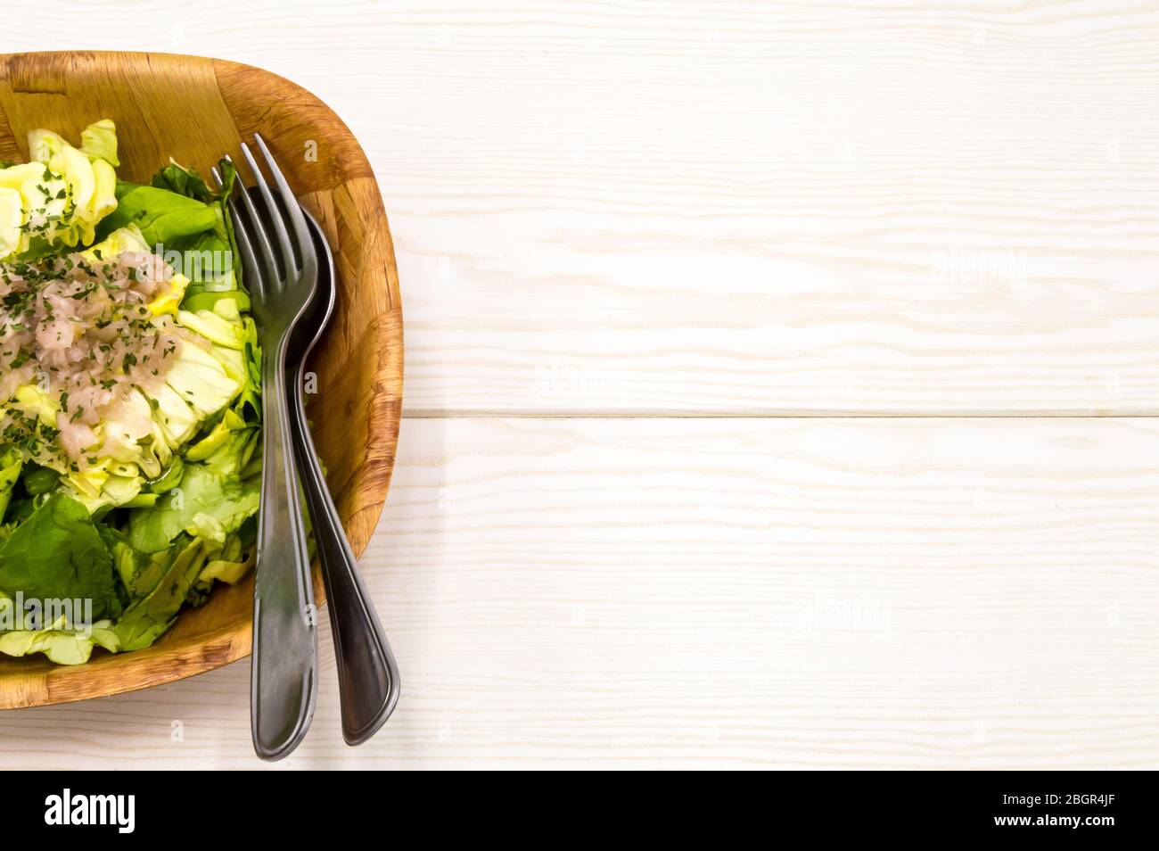 salade de laitue verte fraîche dans un bol isolé sur fond de bois blanc. Banque D'Images salade de laitue verte fraîche dans un bol isolé sur fond de bois blanc. Banque D'Images