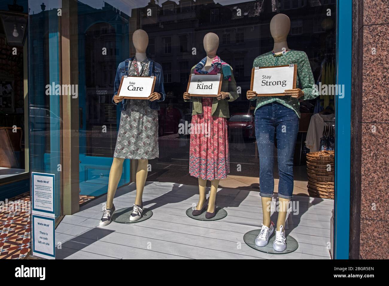 Les mannequins portant des panneaux indiquant « Prenez soin », « soyez gentil » et « soyez fort » dans la fenêtre de White Stuff pendant l'épidémie de Covid-19. Banque D'Images