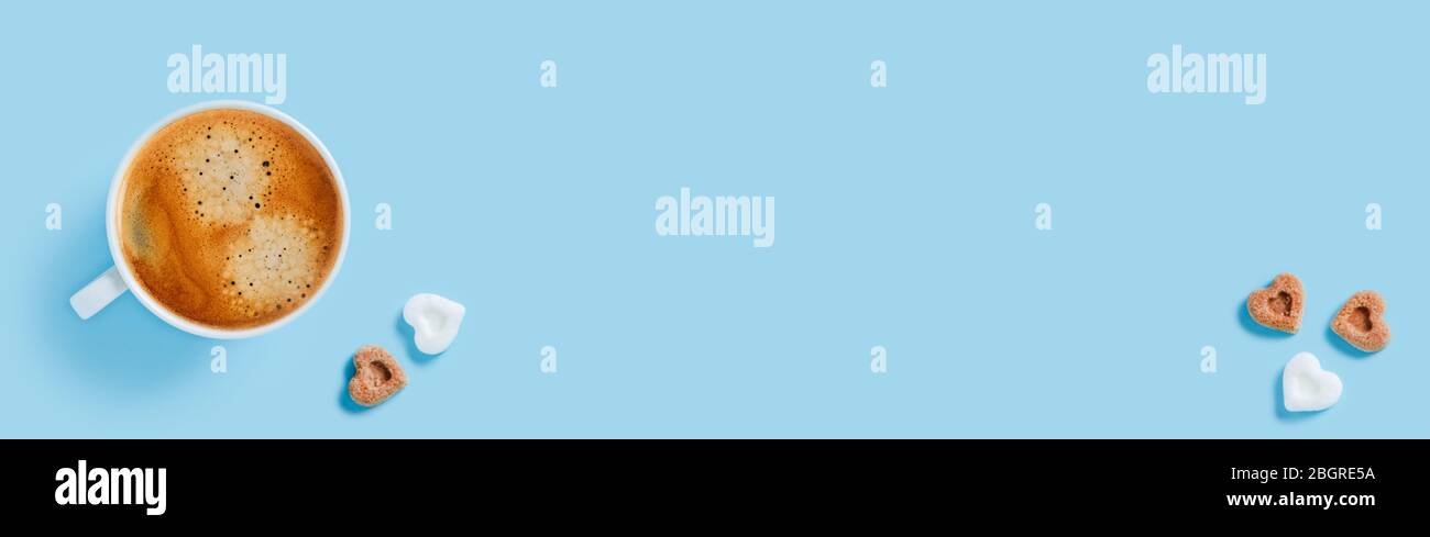Tasse de café fort du matin avec cinq morceaux de sucre en forme de coeur sur fond bleu. Banque D'Images