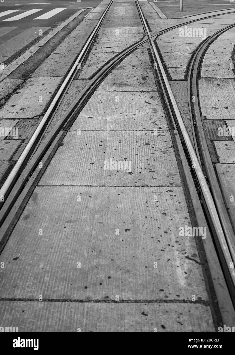 Vue en noir et blanc sur les voies de tramway à une jonction avec des rails qui s'en viennent tout droit ou qui se brandissent à droite. Espace de copie. Pas de gens. Banque D'Images