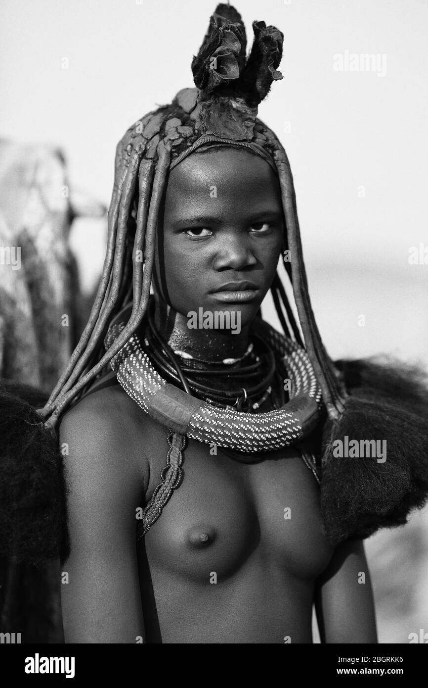 Portrait noir et blanc d'une jeune femme Himba sans seins nus avec une tenue traditionnelle de femmes mariées. Namibie. Banque D'Images