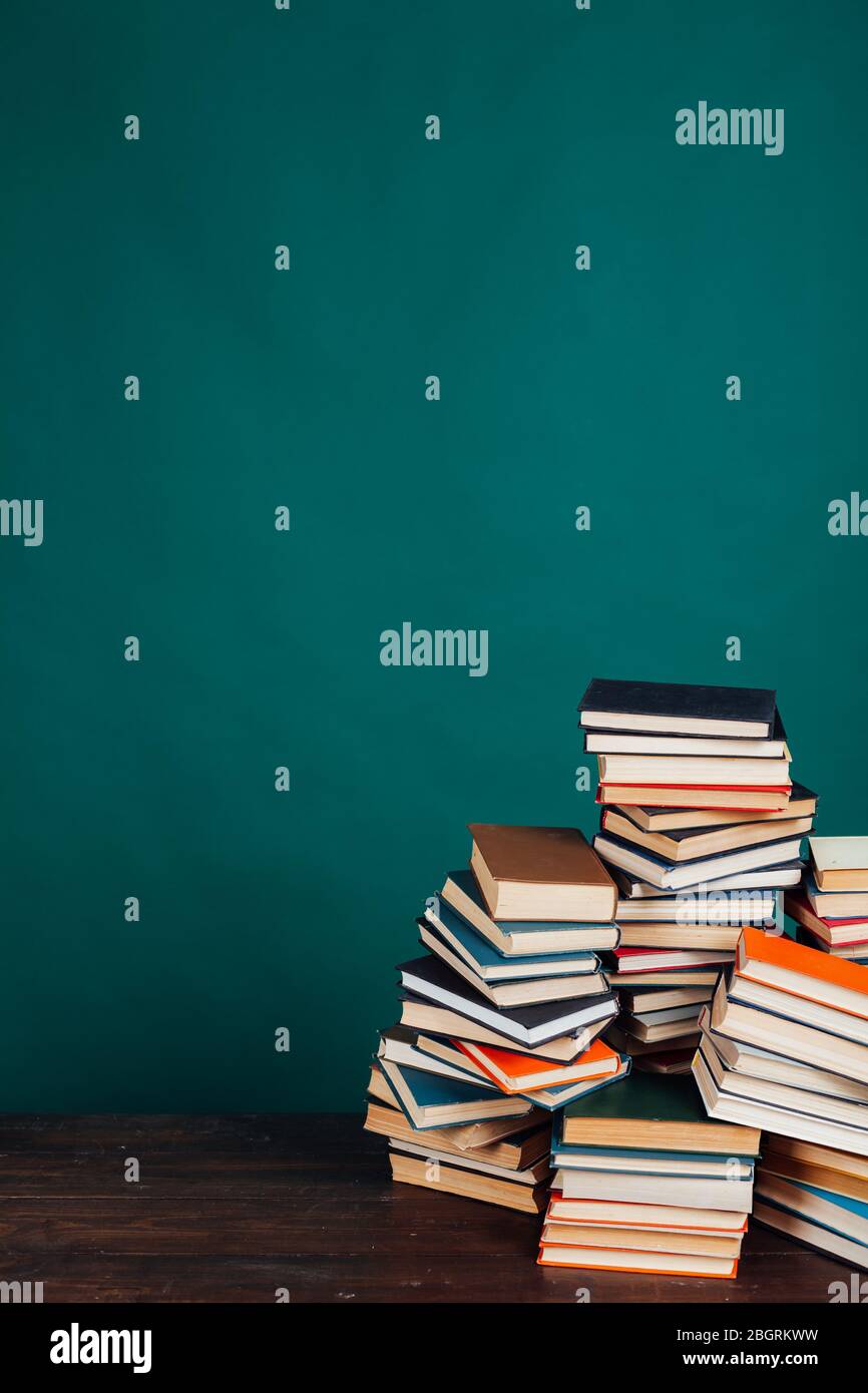 de nombreuses piles de livres éducatifs dans la bibliothèque universitaire sur un fond vert Banque D'Images