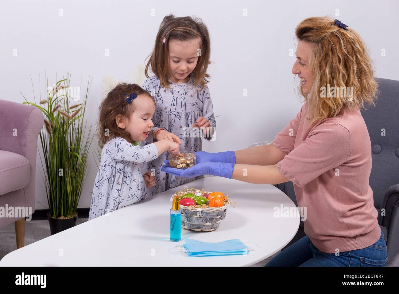 Mère et filles célébrant Pâques, manger des œufs au chocolat. Bonnes vacances en famille. Mignons petites filles riant, souriant et s'amuser. Banque D'Images