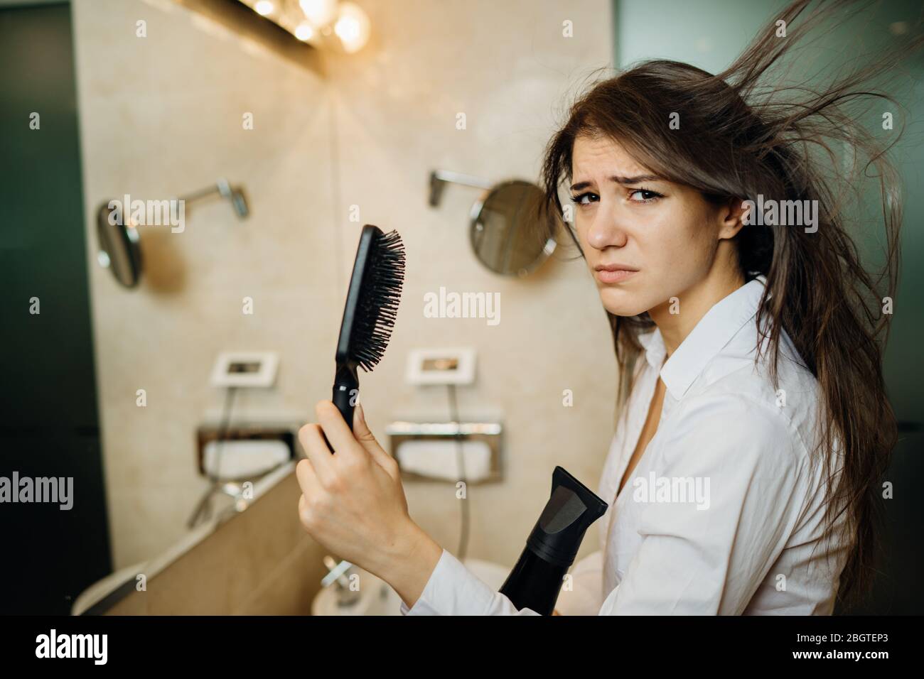 Femme faisant son coiffage avec une brosse à la maison.Bad hair day.routine quotidienne de préparation de coiffure.dégâts de chaleur, extrémités fendues, perte sèche de cheveux.se préparer Banque D'Images