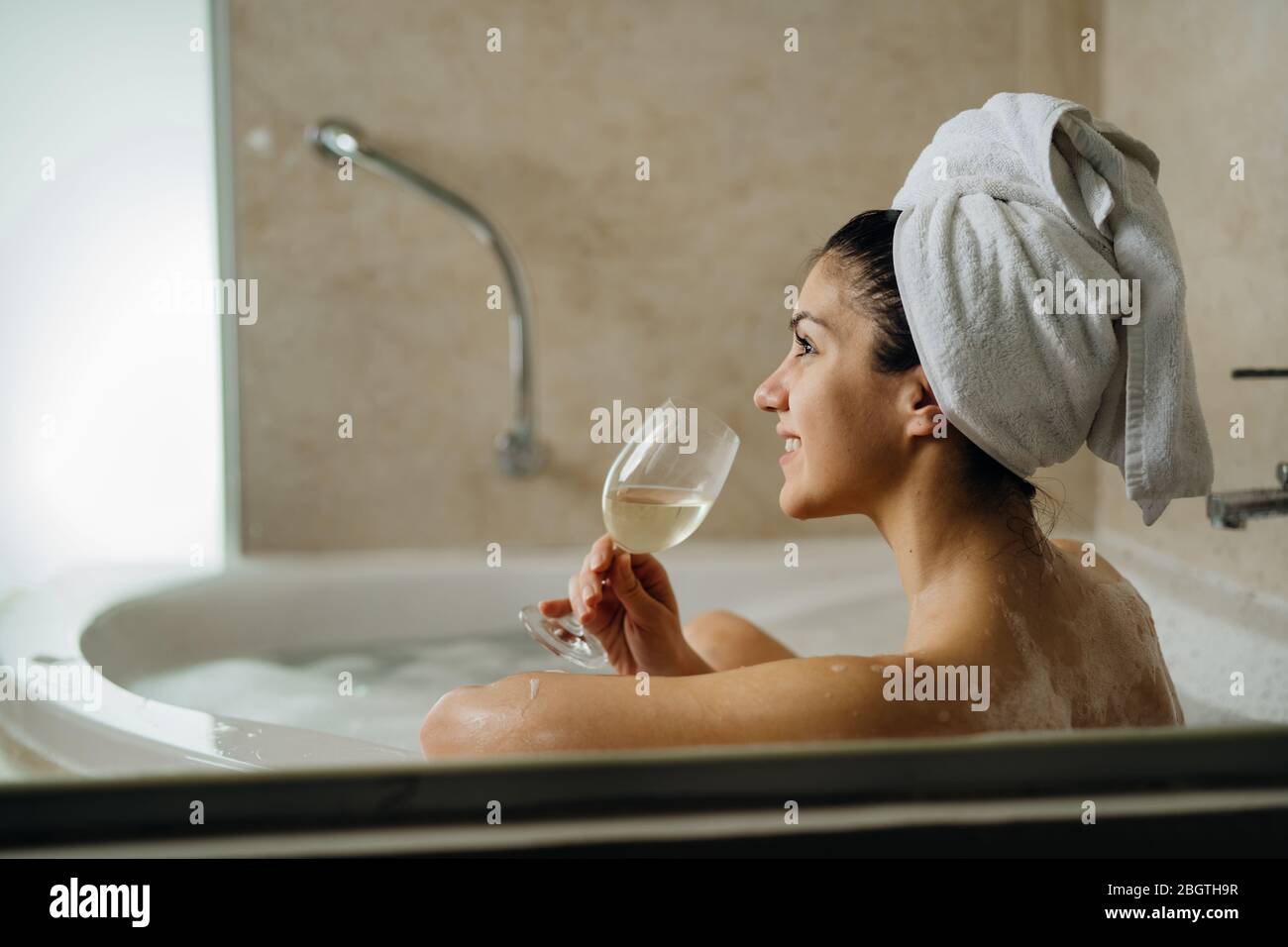 Femme se reposant à la maison dans le bain à remous rituel, vin à boire.détente spa nuit dans la salle de bains.bonne hygiène personnelle routine.peau, soins du corps, aromaathera Banque D'Images