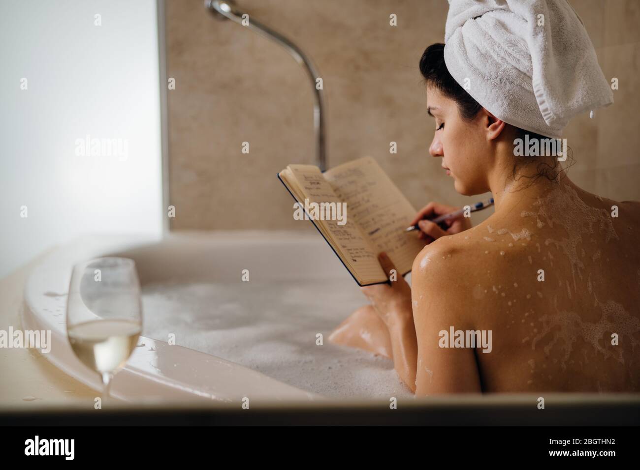 Femme calme ayant un bain relaxant à la maison.Spa nuit d'auto-soin.personne créative inspirée écrivant gratitude agenda/journal.Liste de résolution.faire des plans.WR Banque D'Images