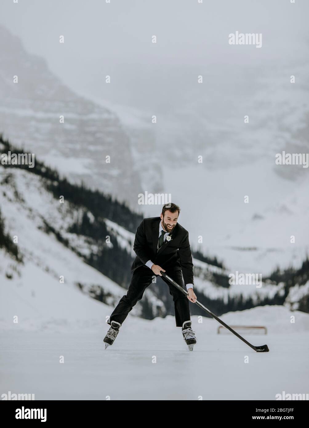 Patins de marié avec bâton de hockey sur Lake Louise, Alberta Banque D'Images