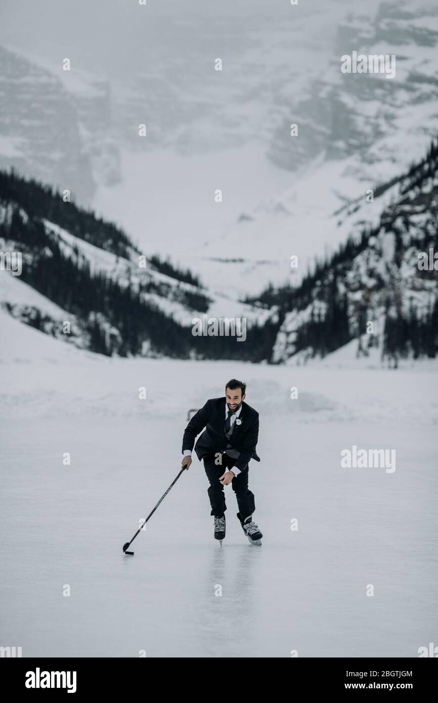 L'homme en costume joue au hockey sur Frozen Lake Louise, Alberta, Canada Banque D'Images