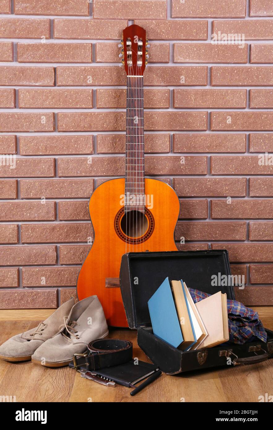 Guitare, baskets et vêtements sur fond de mur de briques Banque D'Images
