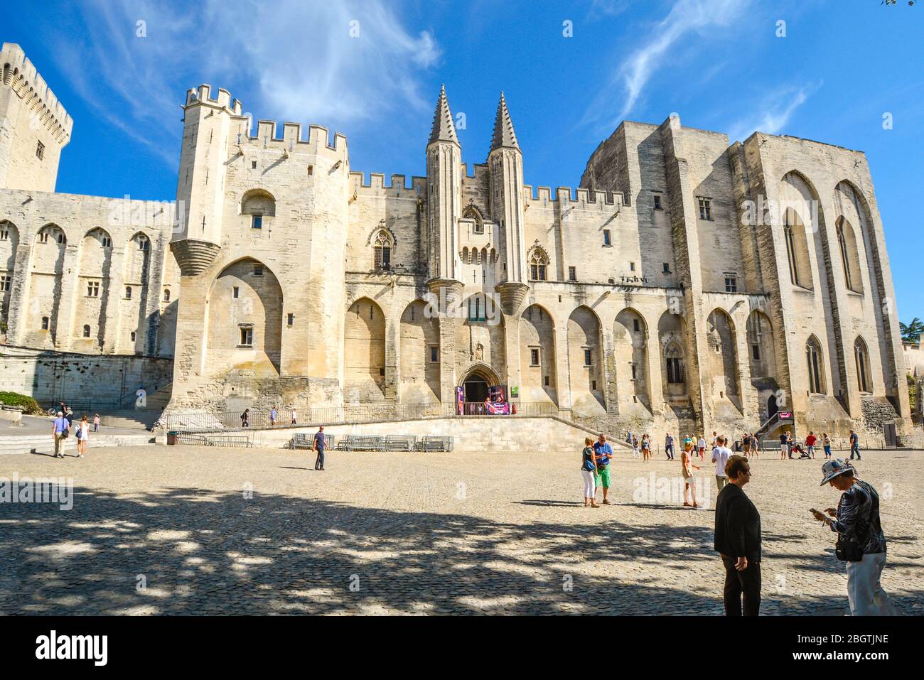 Les touristes se mêlent sur la place devant le Palais des Papes ou le Palais des Papes, un immense château médiéval et forteresse d'Avignon, en France, en Provence Banque D'Images