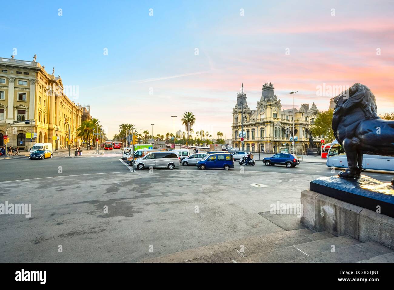 Un lever de soleil coloré vu au-dessus d'une statue de lion de bronze du monument de Columbus au rond-point de la Rambla à Barcelone en Espagne. Banque D'Images