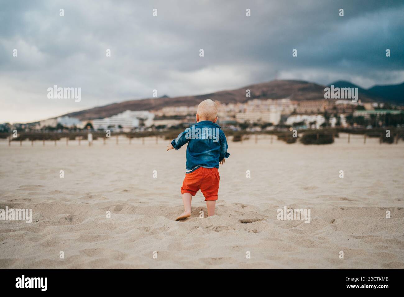 Garçon jouant à la plage par temps nuageux et froid Banque D'Images
